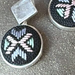 Handcrafted dangling earrings featuring colorful embroidery.